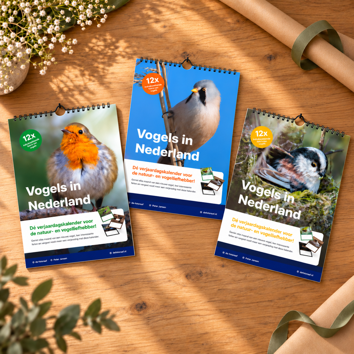 Drie A4 vogelverjaardagskalenders met roodborst, baardman en staartmees op een houten tafel